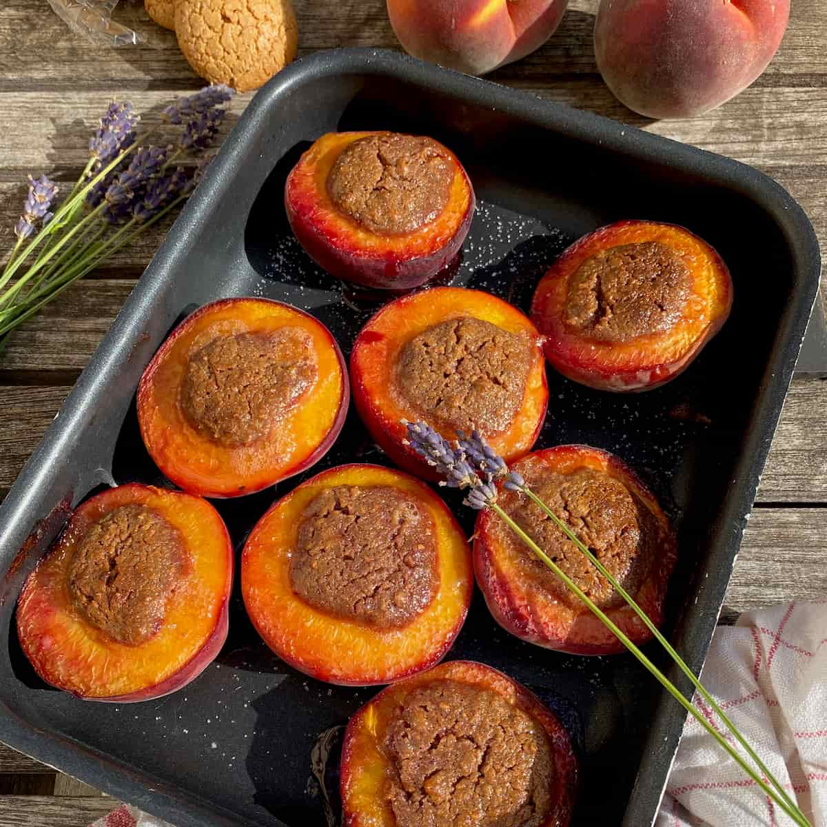 sticky-baked-peaches baking tin with baked peach halves stuffed with amaretti filling and lavender
