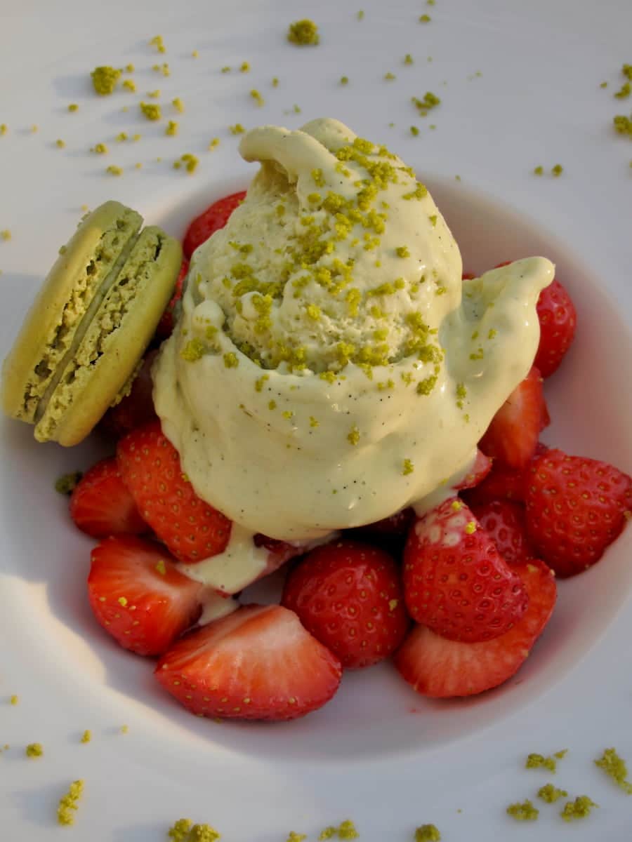 pistachio-wasabi-ice-cream-strawberries-pistachio-macarons large scoop of pistachio ice cream topped with ground pistachios served with strawberries and a pistachio macaron