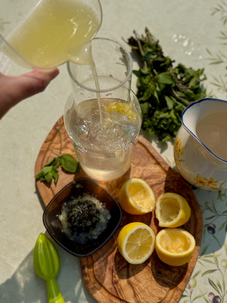pouring freshly squeezed lemon juice into a carafe of water